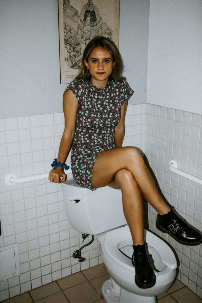 woman sitting on top of toilet